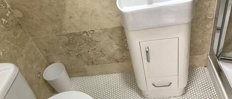 Un baño con inodoro, lavamanos y un armario para guardar cosas.