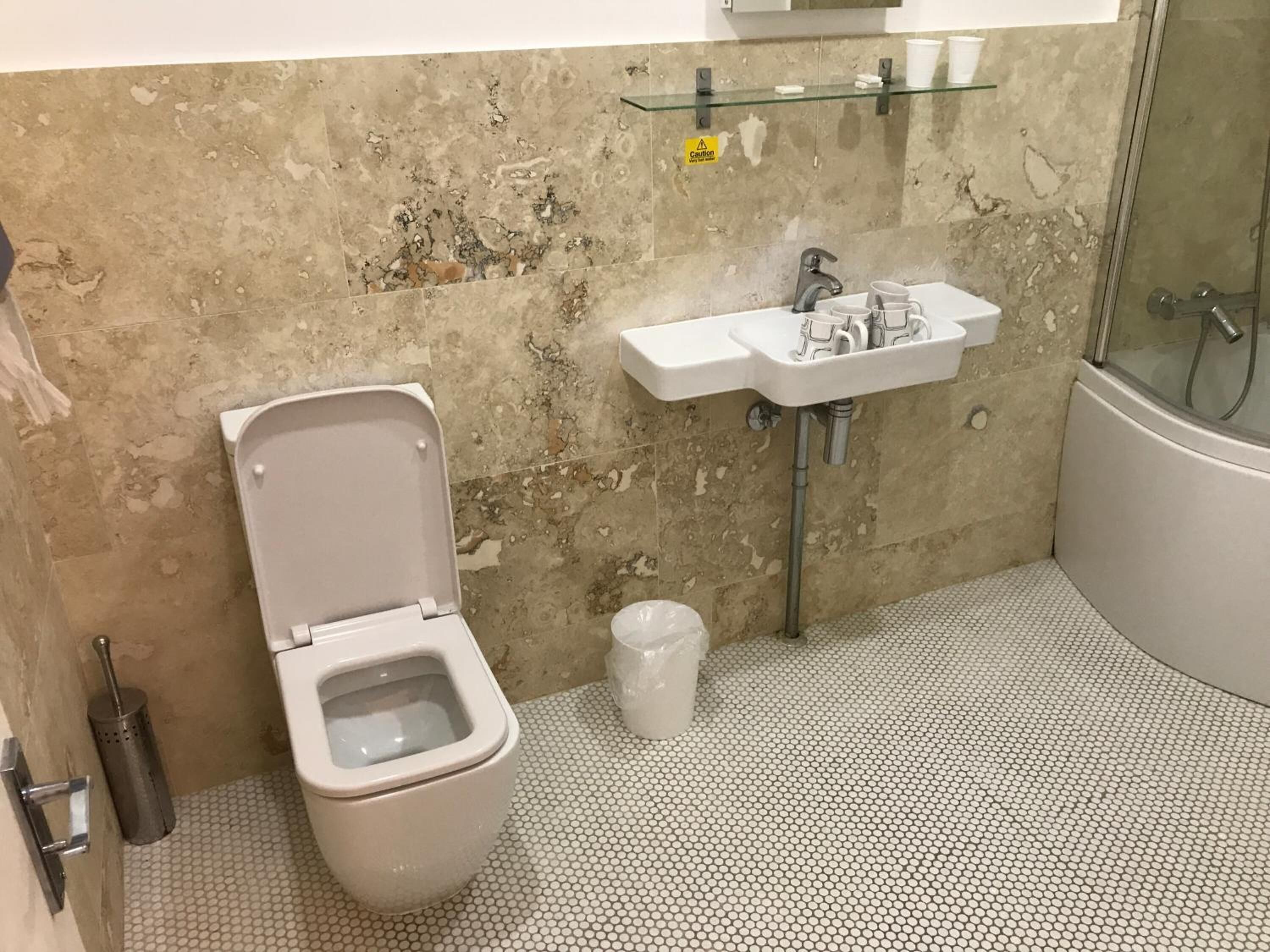 A bathroom with a toilet, sink, and shower.