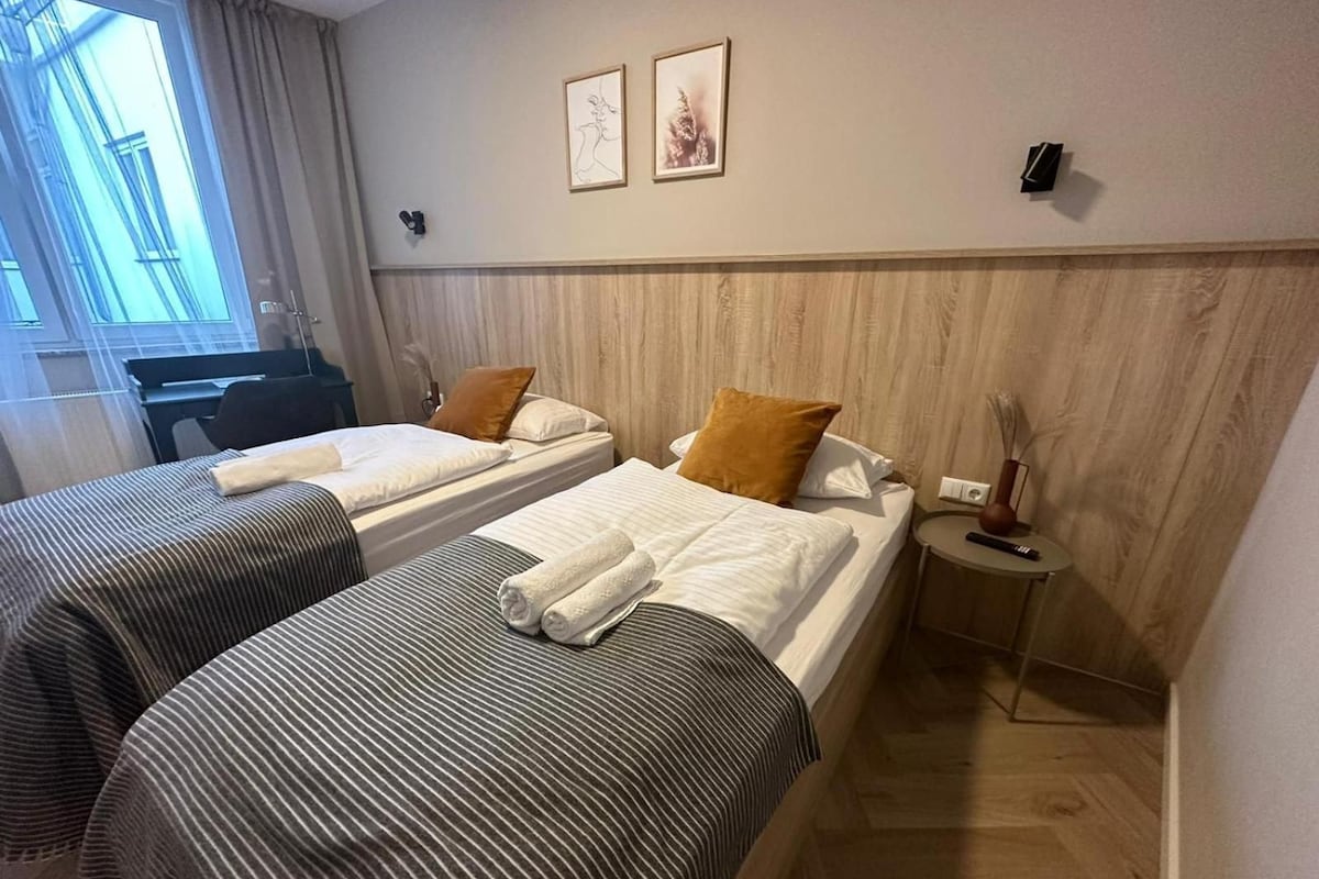 A hotel room with two beds, a desk, and a small side table.