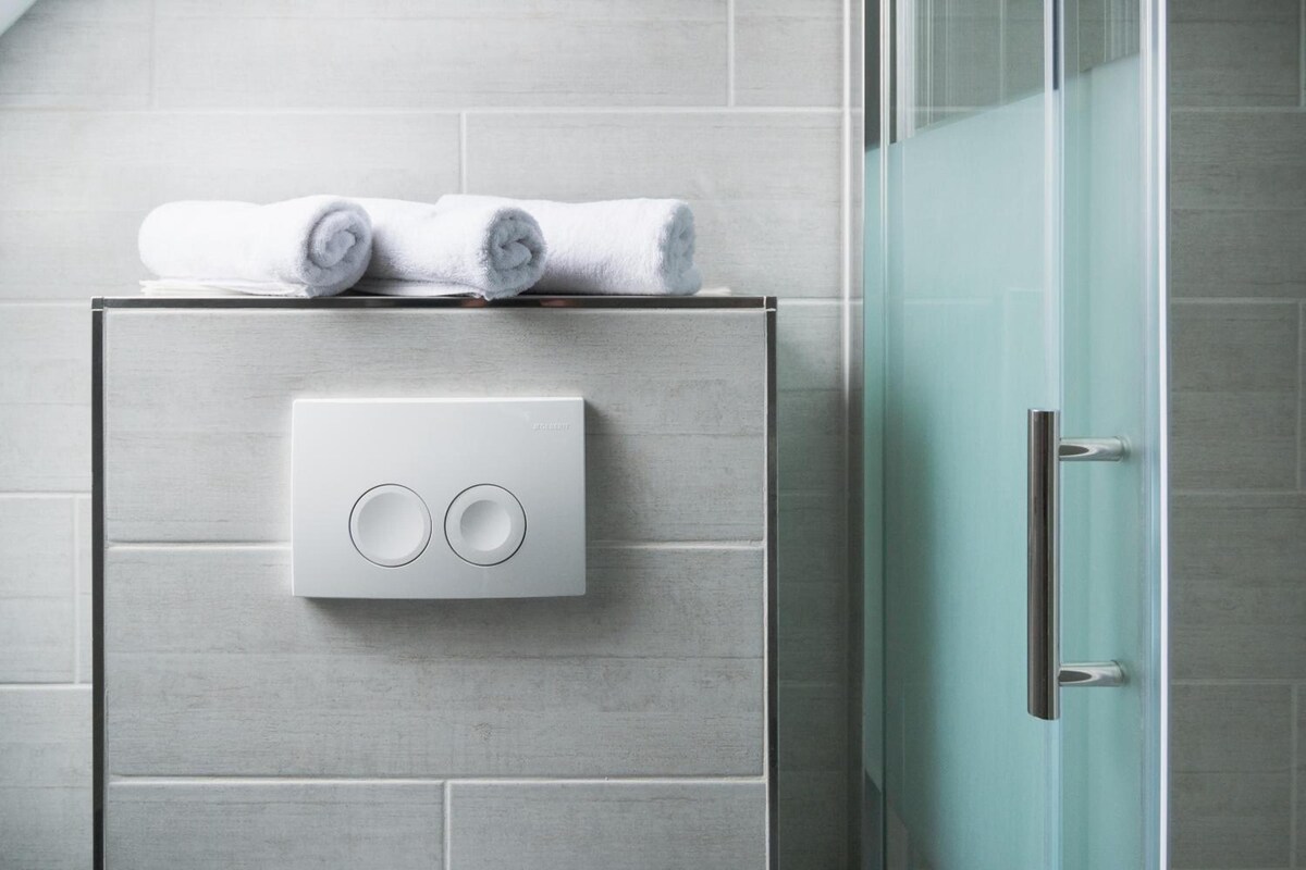 A bathroom with a towel warmer, a glass shower door, and a tiled wall.
