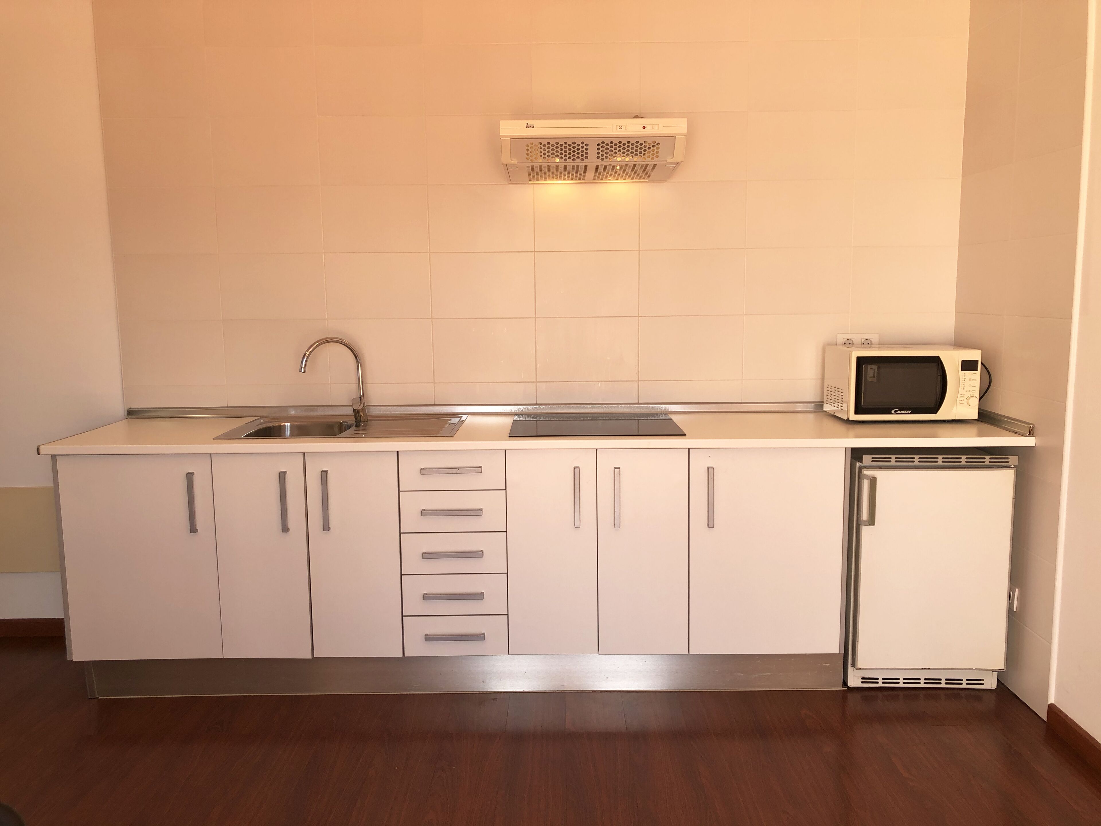 A compact kitchen with a sink, microwave, and built-in oven.