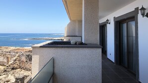 A coastal building with a stone facade, a balcony overlooking the sea, and a modern entrance with glass doors. - Cotillo Ocean View (La Oliva)
