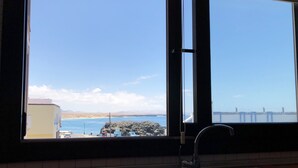 A kitchen with a large window overlooking a coastal view. - Cotillo Ocean View (La Oliva)