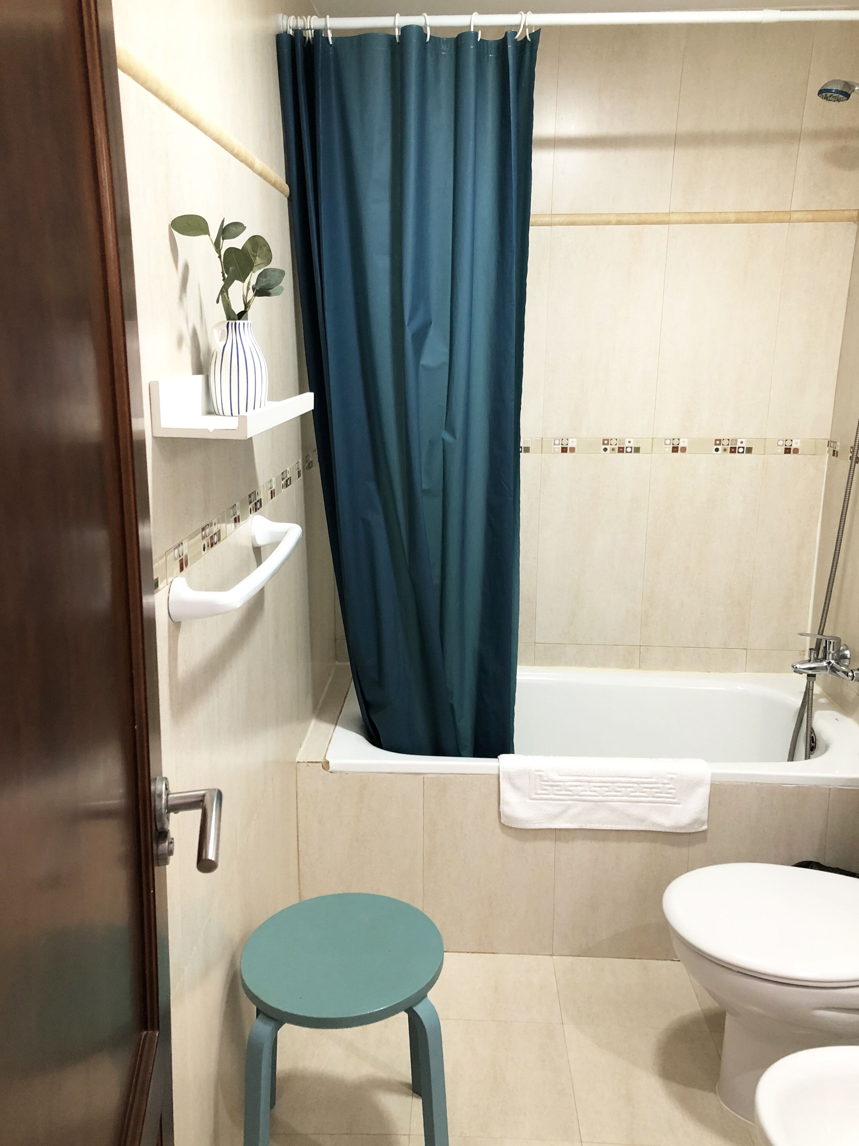 Une salle de bain avec une baignoire, des toilettes et un petit tabouret.
