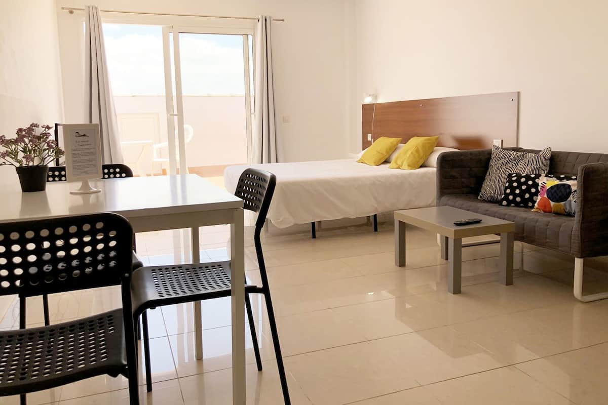 A hotel room with a bed, a sofa, a table, and a chair.