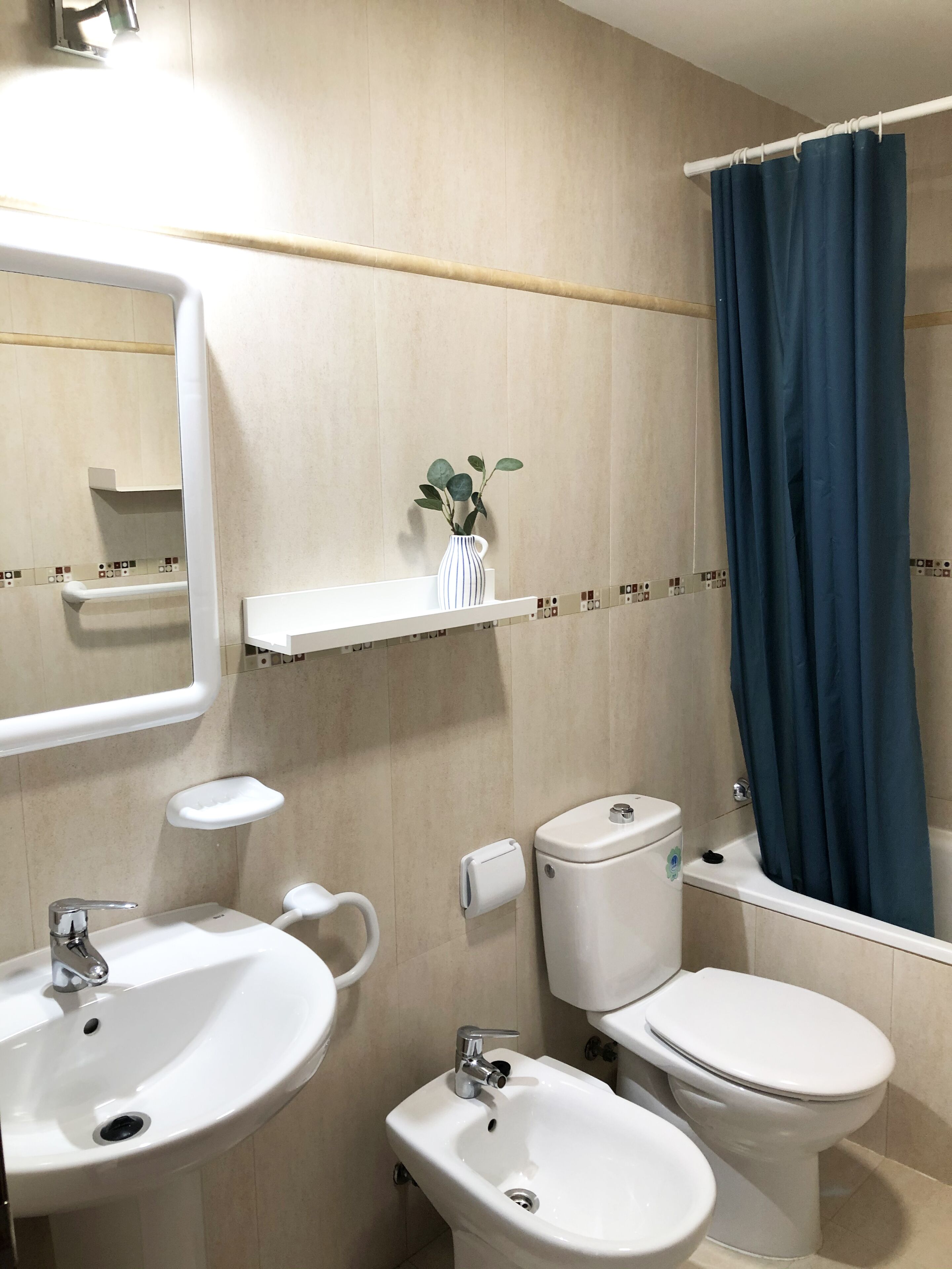 Une salle de bain avec deux lavabos, des toilettes, un rideau de douche et un miroir.