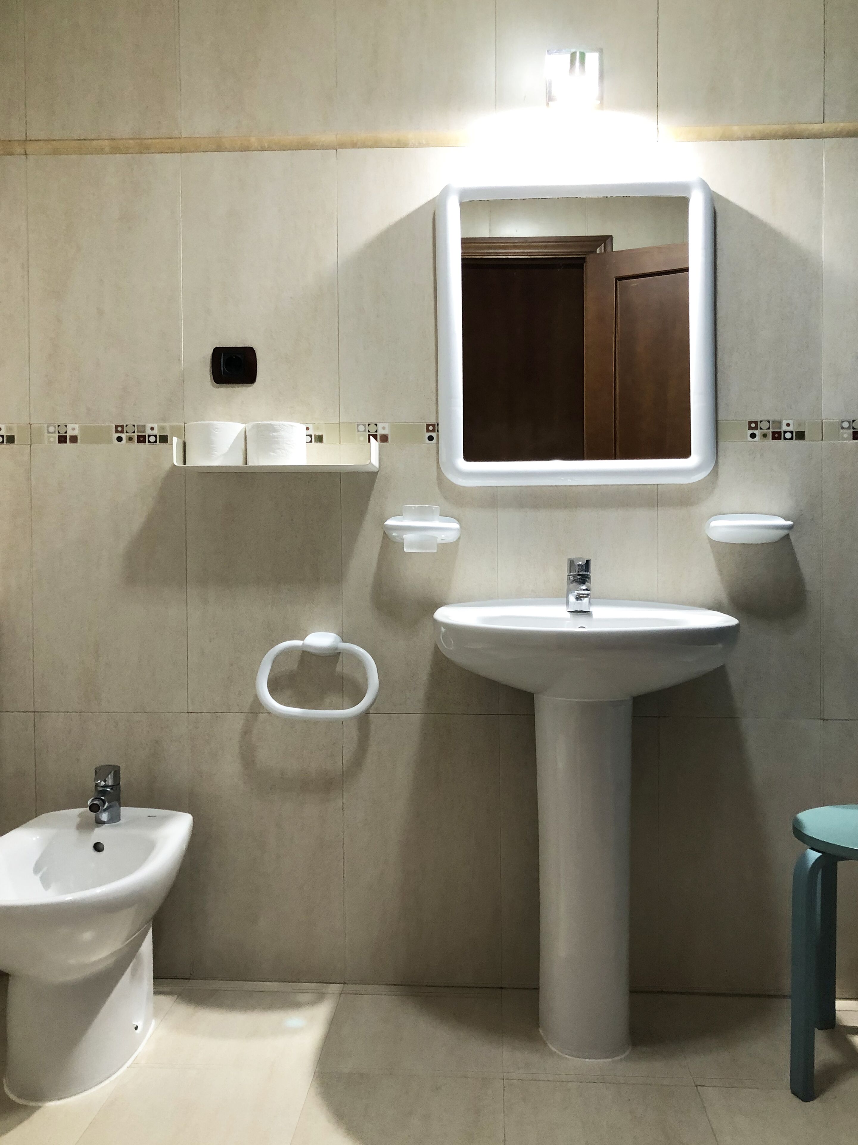 A bathroom with a pedestal sink, a bidet, and a mirror.
