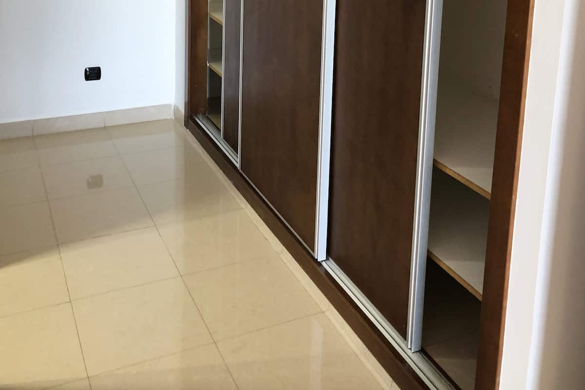A room with a sliding door closet, a tiled floor, and a light switch on the wall.