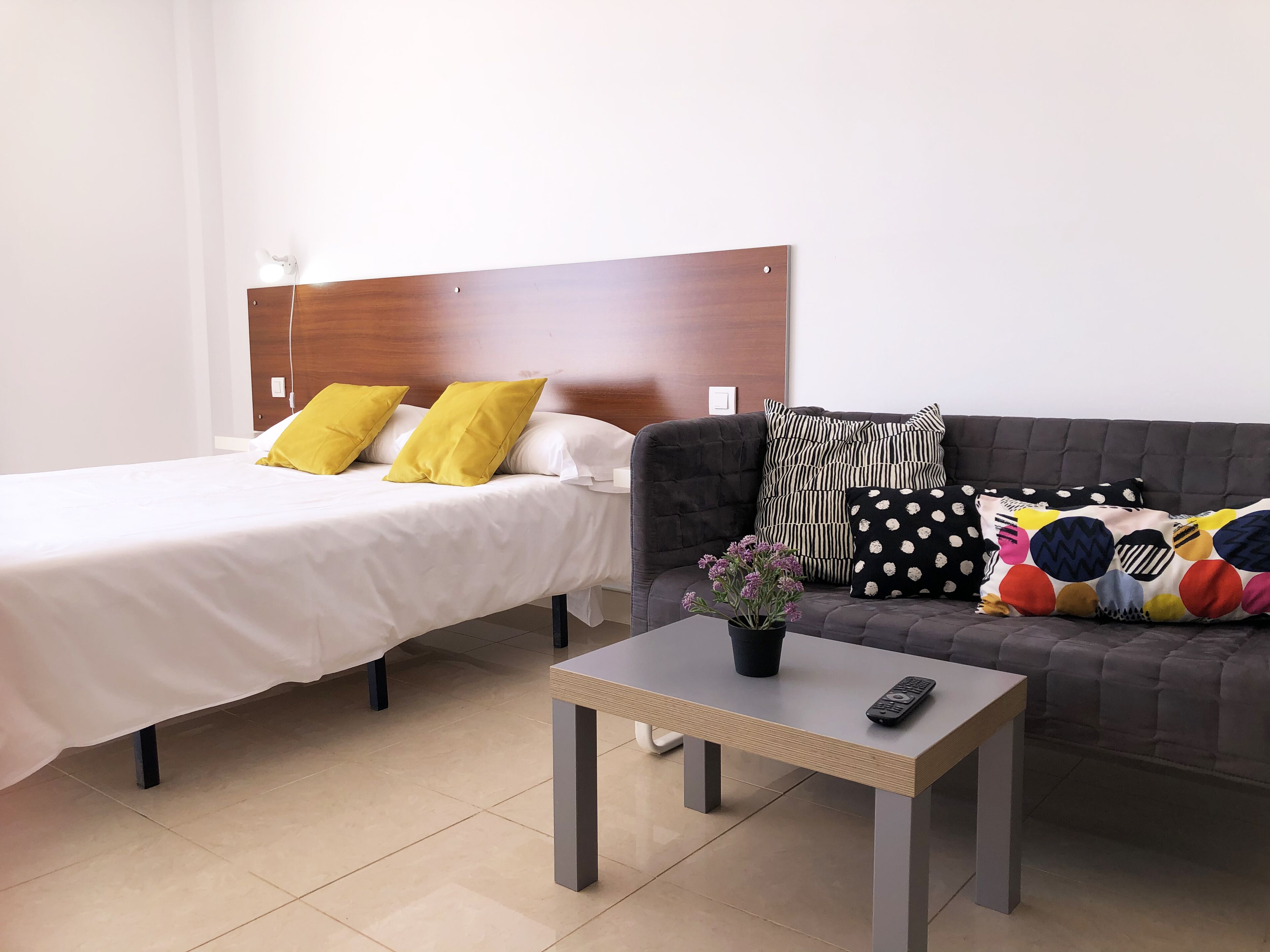 Een hotelkamer met twee bedden, een bank, een kleine tafel en een afstandsbediening op de tafel.