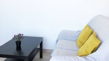 A room with a light-colored sofa, a black coffee table with a potted plant, and a framed picture on the wall.