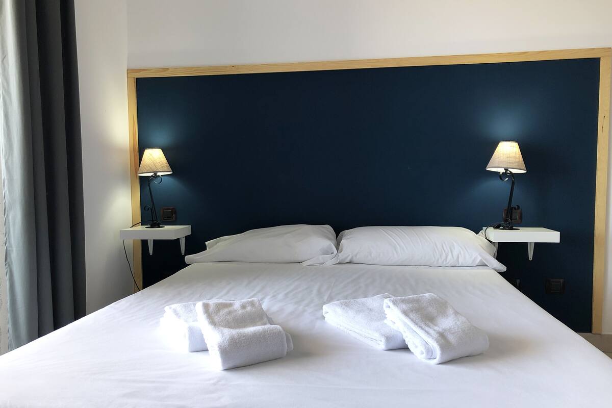 A hotel room with a large bed, two bedside tables with lamps, and a headboard.