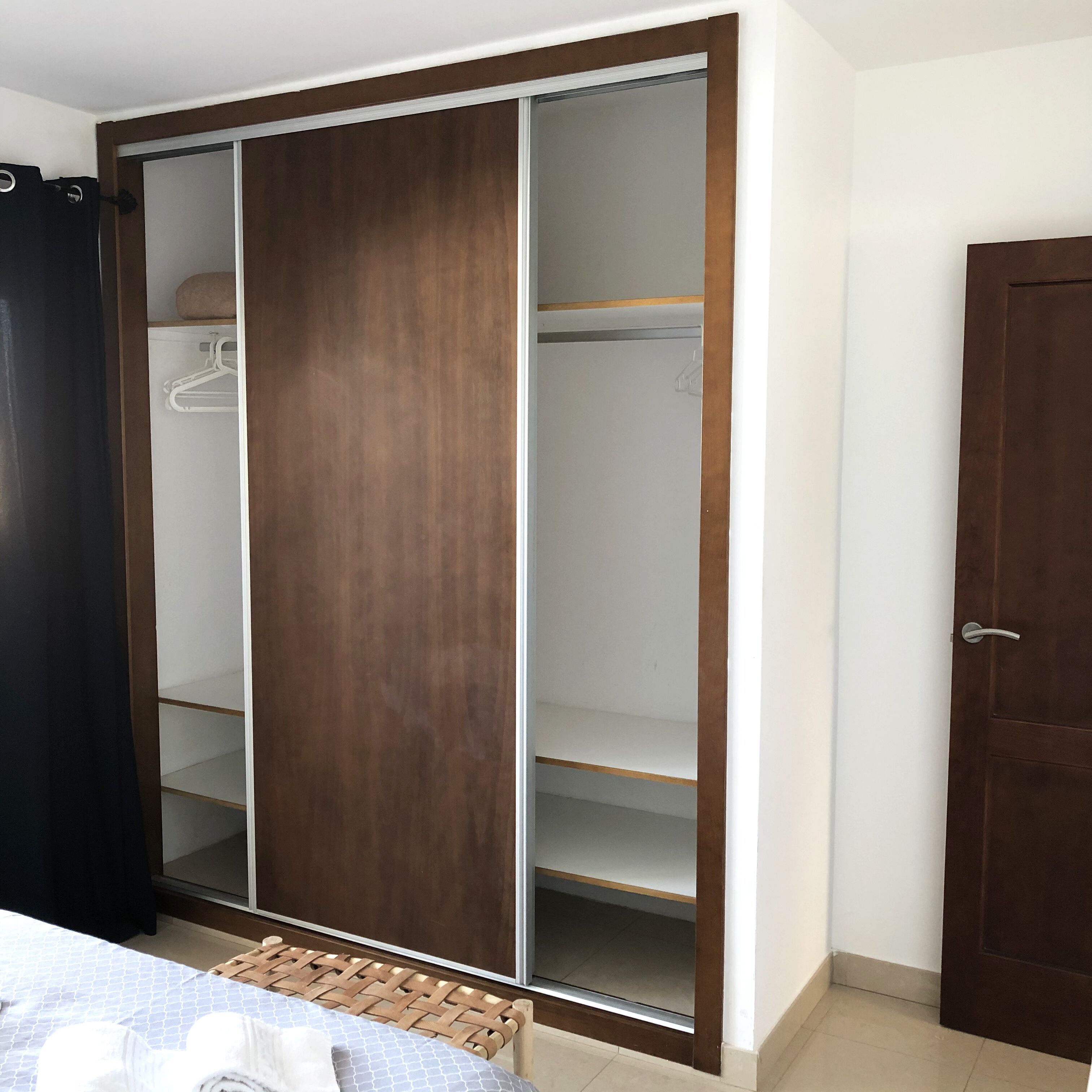 A room with a large wardrobe featuring multiple shelves and hanging space.