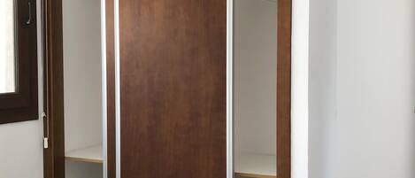 Une chambre à coucher avec une armoire en bois, un lit et une petite table.