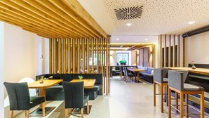 A modern interior with wooden slats, seating areas, and a central walkway. - Hotel Hirschentenne (Stams)