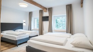 A hotel room with two beds, a wooden ceiling, and large windows. - Hotel Hirschentenne (Stams)