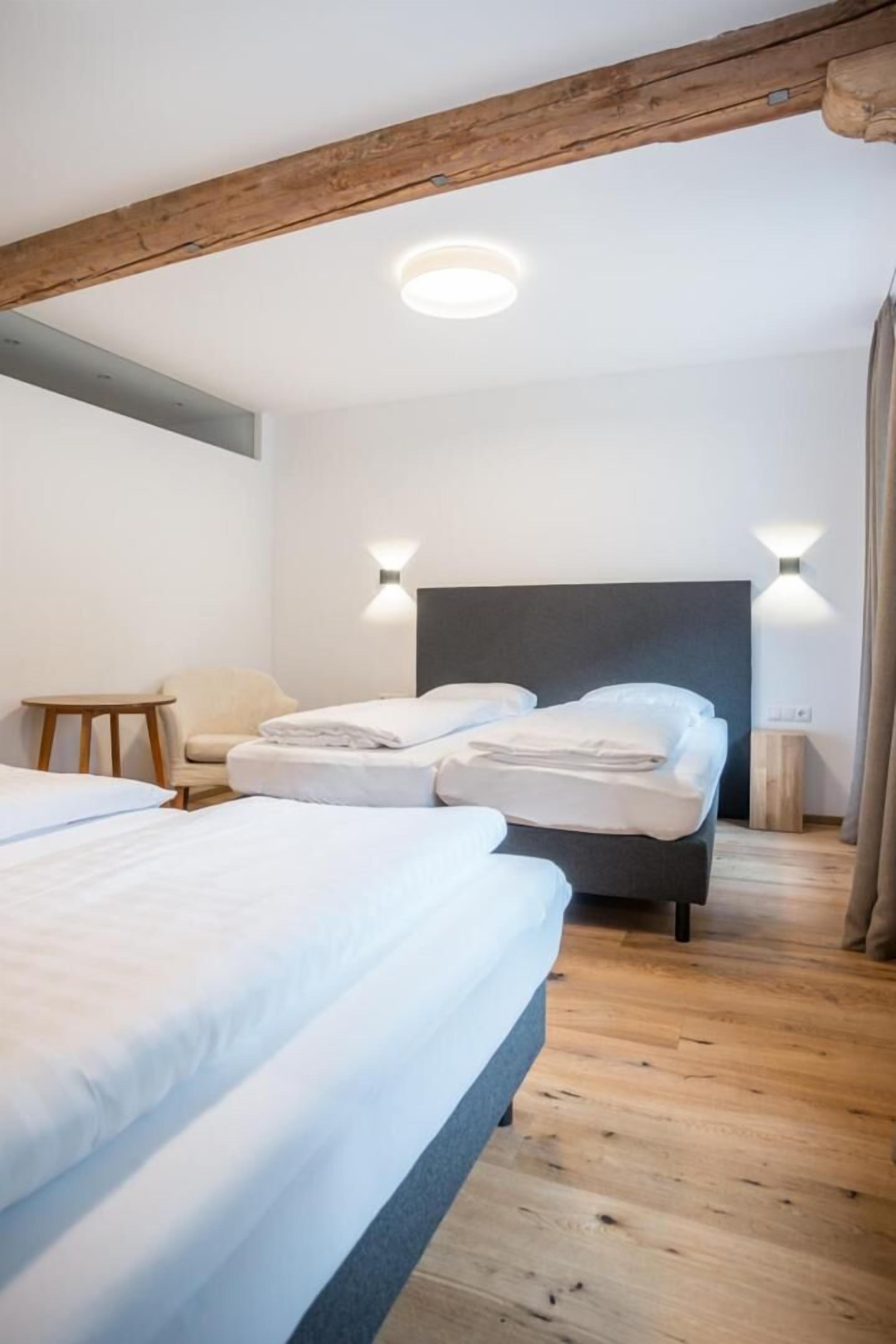 Habitación de hotel con dos camas, techo de madera y dos luces fijadas a la pared.