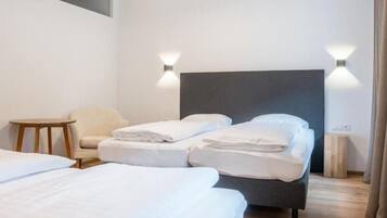 Habitación de hotel con dos camas, techo de madera y dos luces fijadas a la pared.