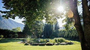 A serene outdoor setting with a pond, rocks, and trees. - Hotel Hirschentenne (Stams)