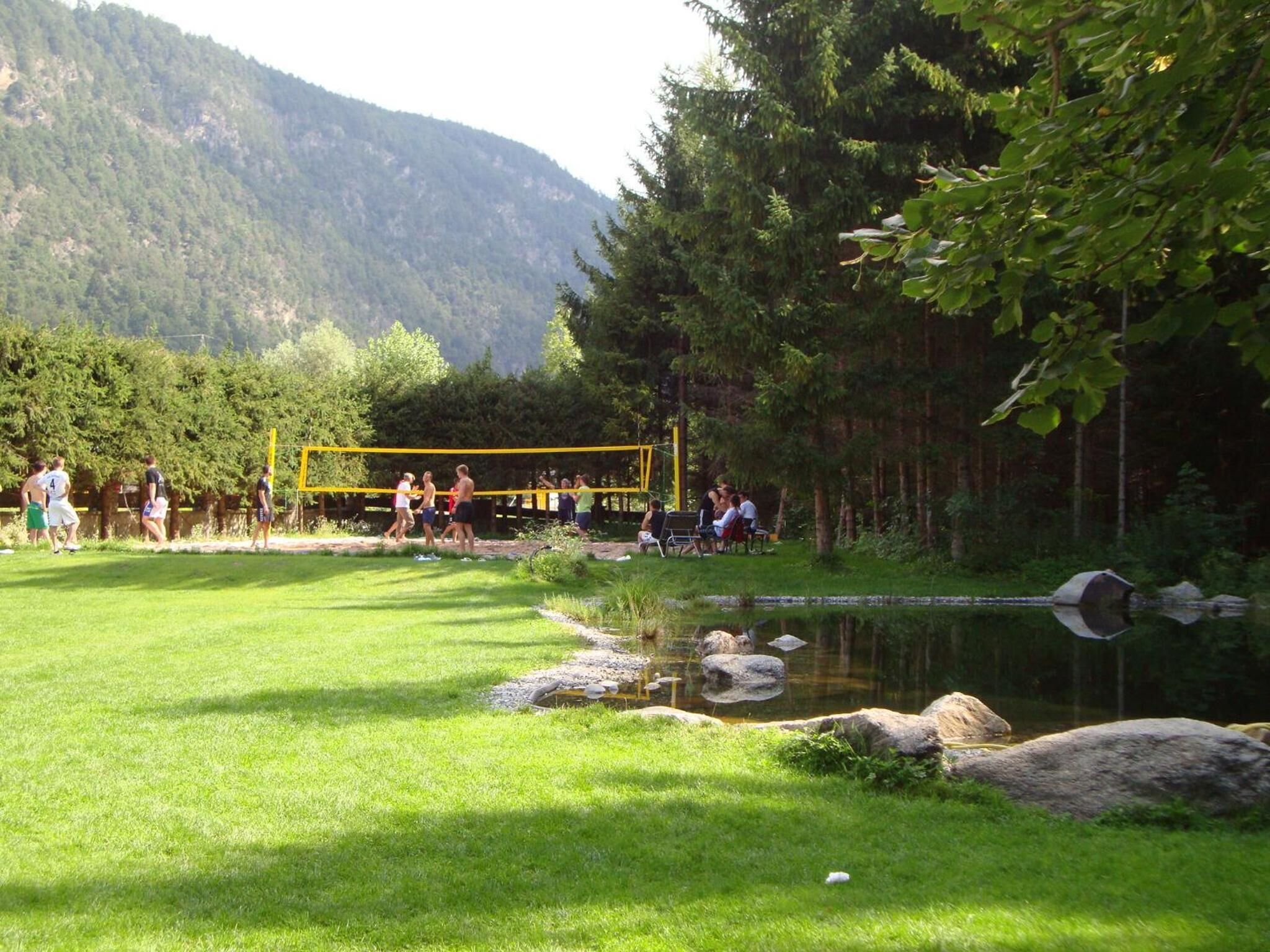 A grassy area with a pond, trees, and a yellow structure.