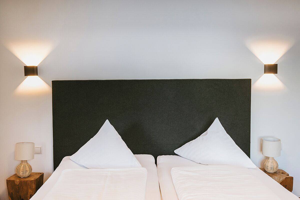A double bed with a dark headboard, two bedside lamps, and a nightstand with a lamp.