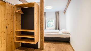 Una habitación con un armario de madera, una cama y un ventanal con cortinas.