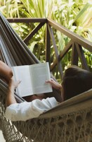 A hammock with a person reading a book, surrounded by greenery.