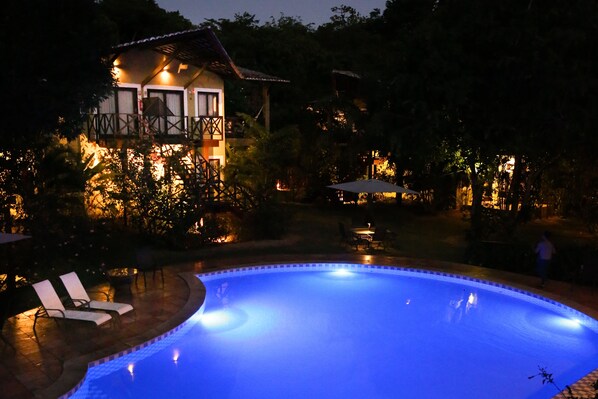 Una piscina con sillas de descanso y una casa al fondo.