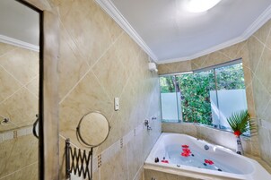 Un baño con bañera, ventana con vistas a la vegetación y un perchero para toallas.