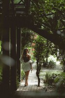 Un sendero atraviesa un jardín exuberante, con una estructura de madera a la izquierda.