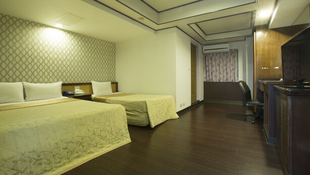 A hotel room with two beds, a desk with a chair, and a television. - Chief Hotel (Hsinchu)