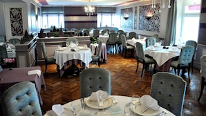 A dining area with multiple tables and chairs, chandeliers, and patterned wall designs. - Hôtel la Croix Couverte (Mayenne)