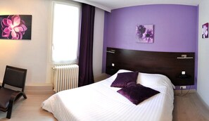 A bedroom with a bed, a chair, a radiator, and purple curtains. - Hôtel la Croix Couverte (Mayenne)