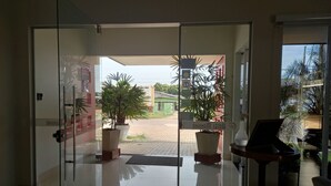 A hotel entrance with glass doors, potted plants, a tiled floor, and a view of the outside area. - Hotel Mandino (Alta Floresta)