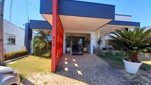 A modern building with a red and blue facade, a paved entrance, and surrounding greenery. - Hotel Mandino (Alta Floresta)