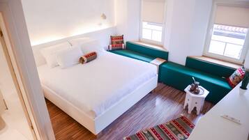 A modern bedroom with a large bed, a green sofa, and a small side table with a decorative item.