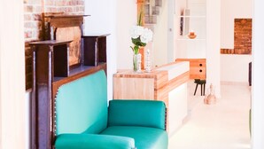 A modern living room with a teal sofa, a wooden coffee table, and a brick accent wall. - Hotel Old Sarajevo (Sarajevo)