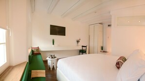 A modern bedroom with a large bed, a green sofa, a small side table, and a mirror. - Hotel Old Sarajevo (Sarajevo)