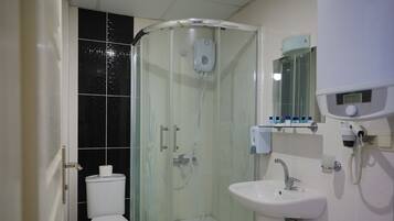 A bathroom with a glass-enclosed shower, a toilet, and a sink.