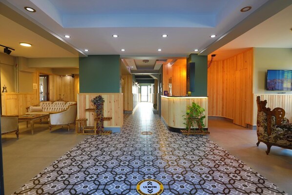 A hotel lobby with a patterned floor, wooden furniture, and a reception desk. - Kayi Apart Hotel (Bolu)