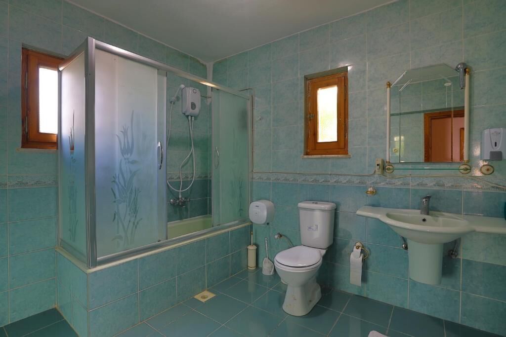 Un baño con ducha, inodoro, lavabo y ventana.