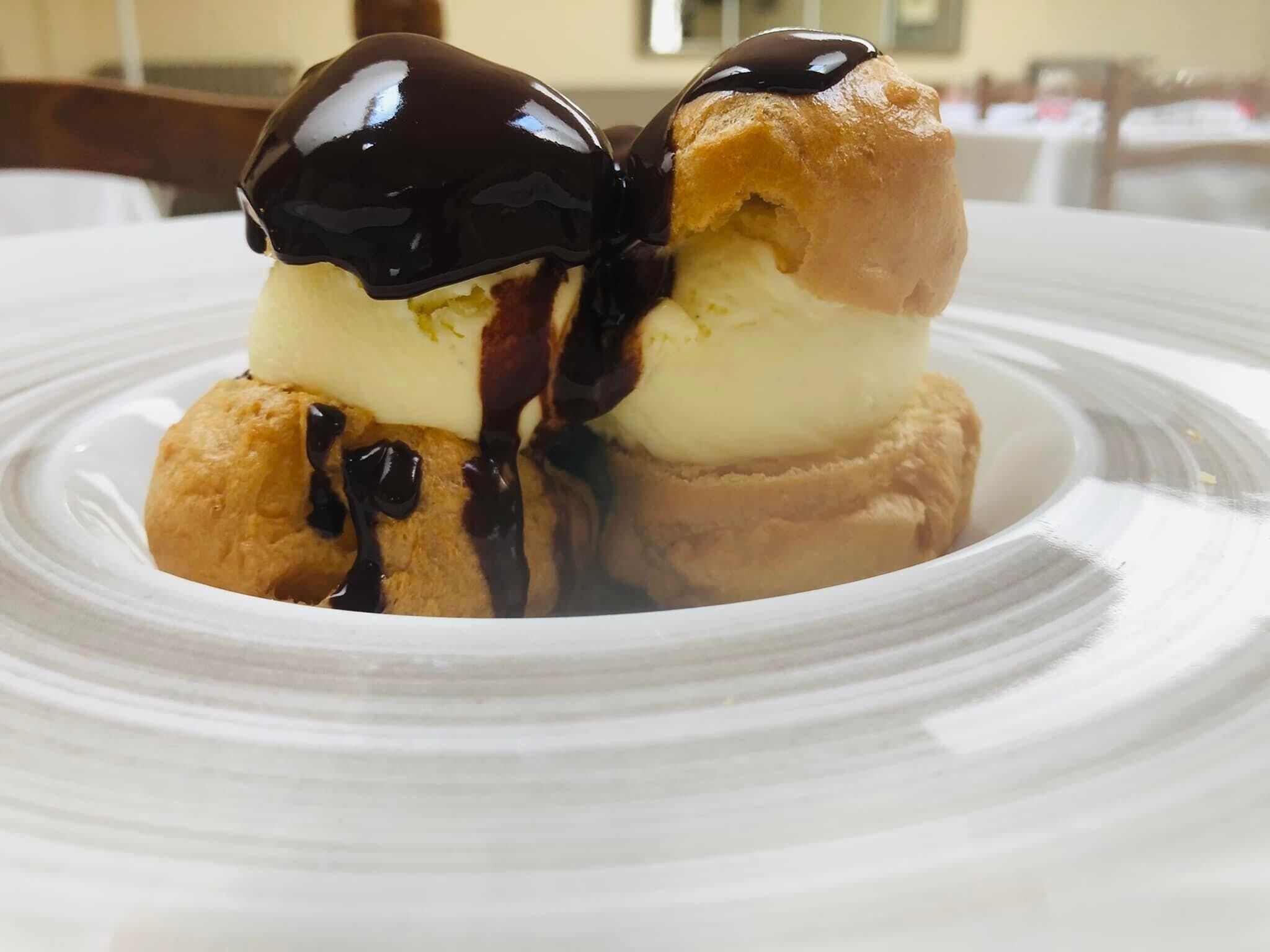 Un dessert composto da gelato e salsa al cioccolato su un piatto bianco.