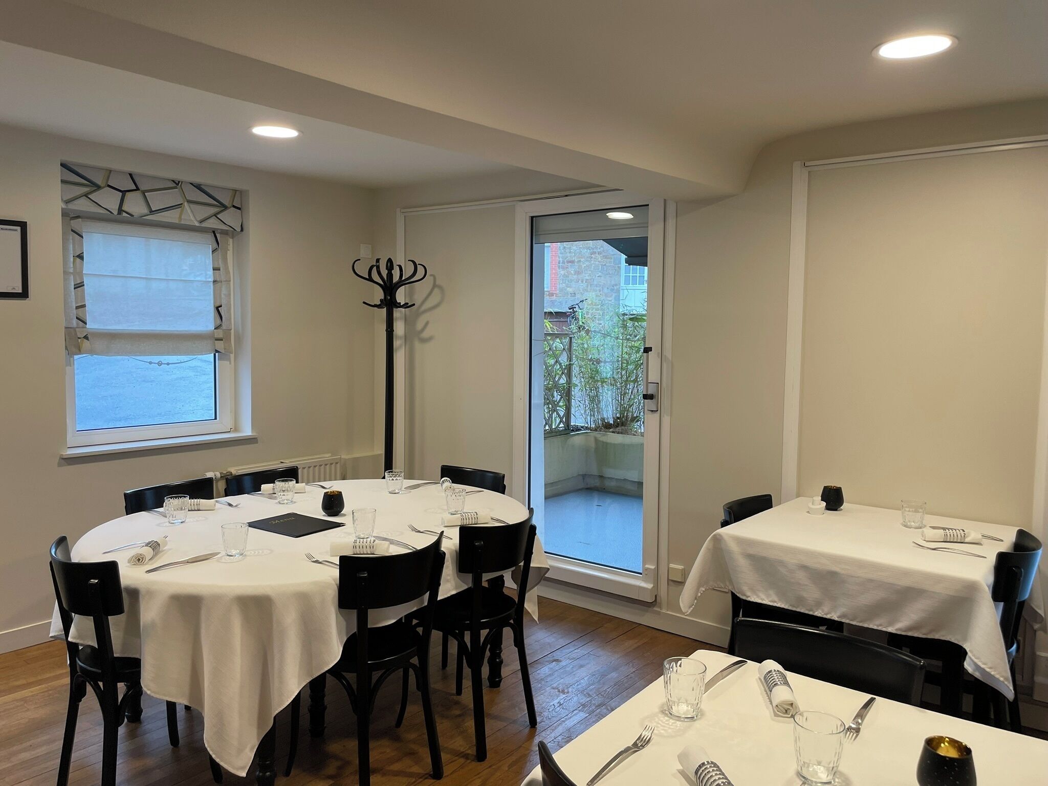 A dining area with round tables, black chairs, and white tablecloths.