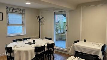 A dining area with round tables, black chairs, and white tablecloths.