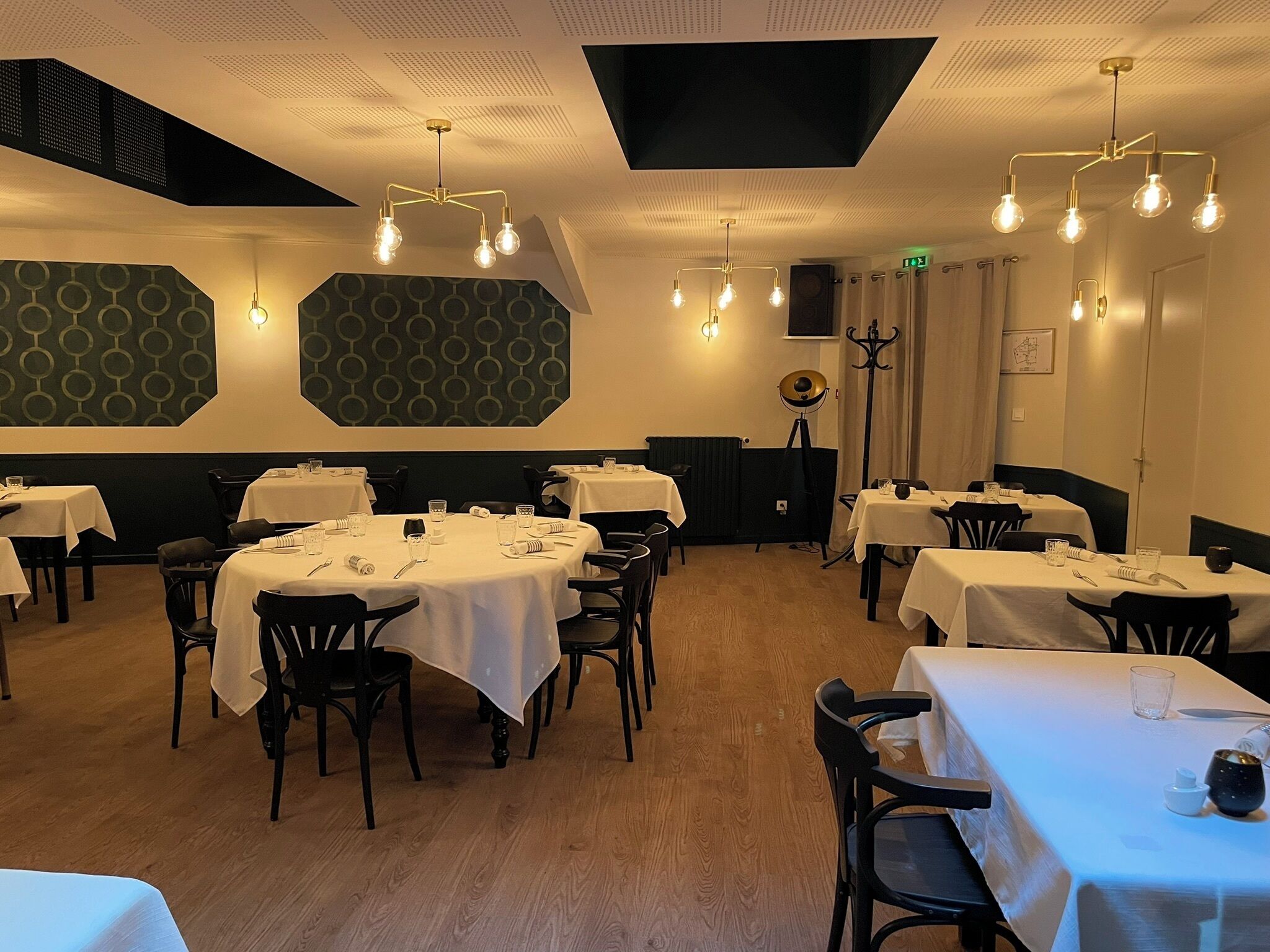 A restaurant with round tables, black chairs, and a patterned wall.