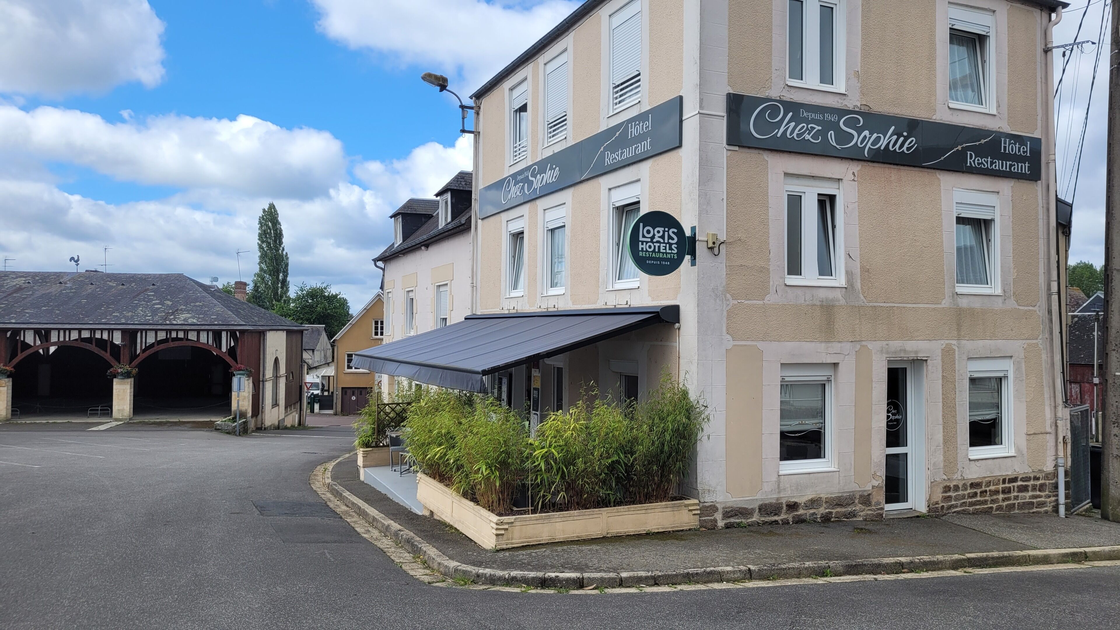 Un hotel amb un cartell que diu 'Chez Sophie' i 'Hotel Restaurant', i un logotip de 'Logis Hotels Restaurants'.