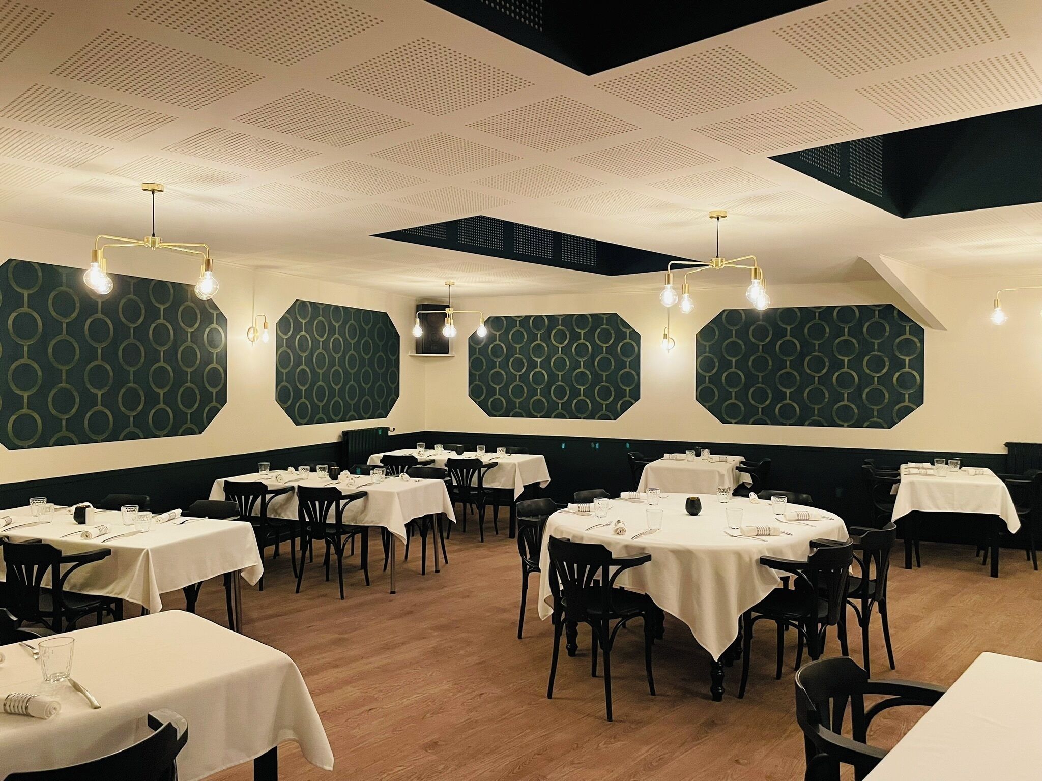 Een restaurant met verschillende tafels en stoelen, geometrische wanddecoraties en een houten vloer.