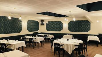 Een restaurant met verschillende tafels en stoelen, geometrische wanddecoraties en een houten vloer.