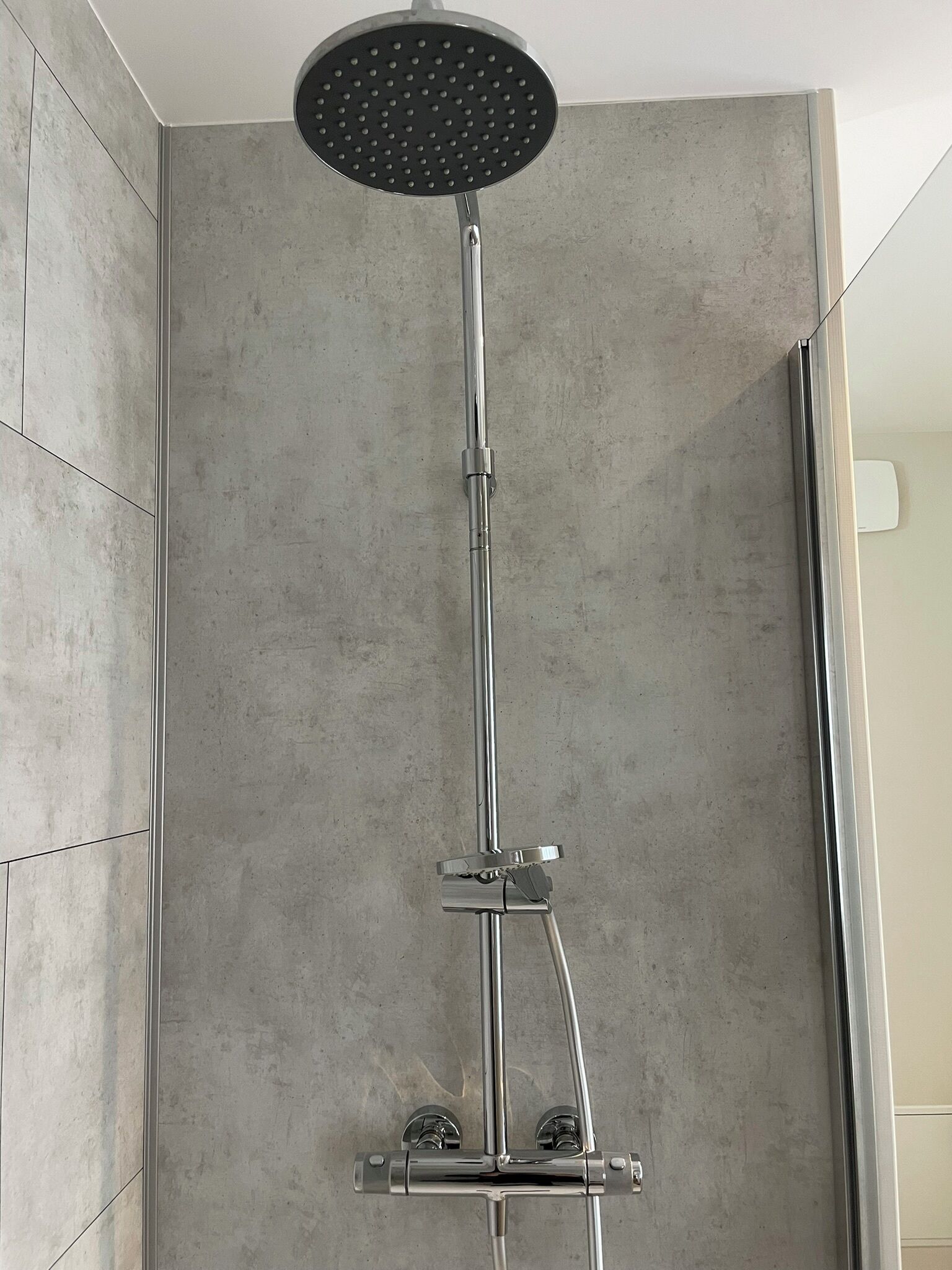 Une douche moderne dotée d’un pommeau rond et d’accessoires chromés.