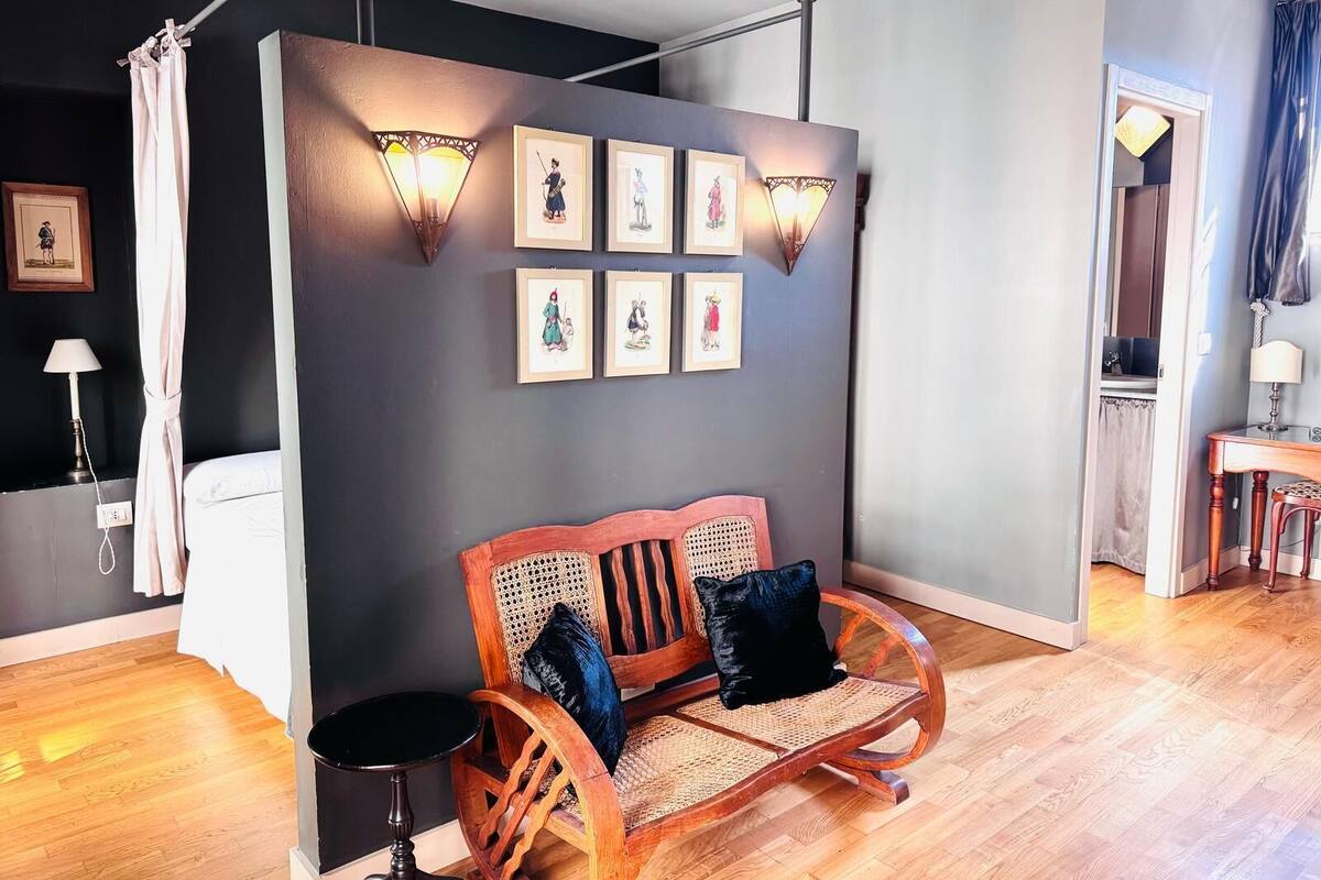 Una habitación con un banco de madera, una lámpara de pared y obras de arte enmarcadas.