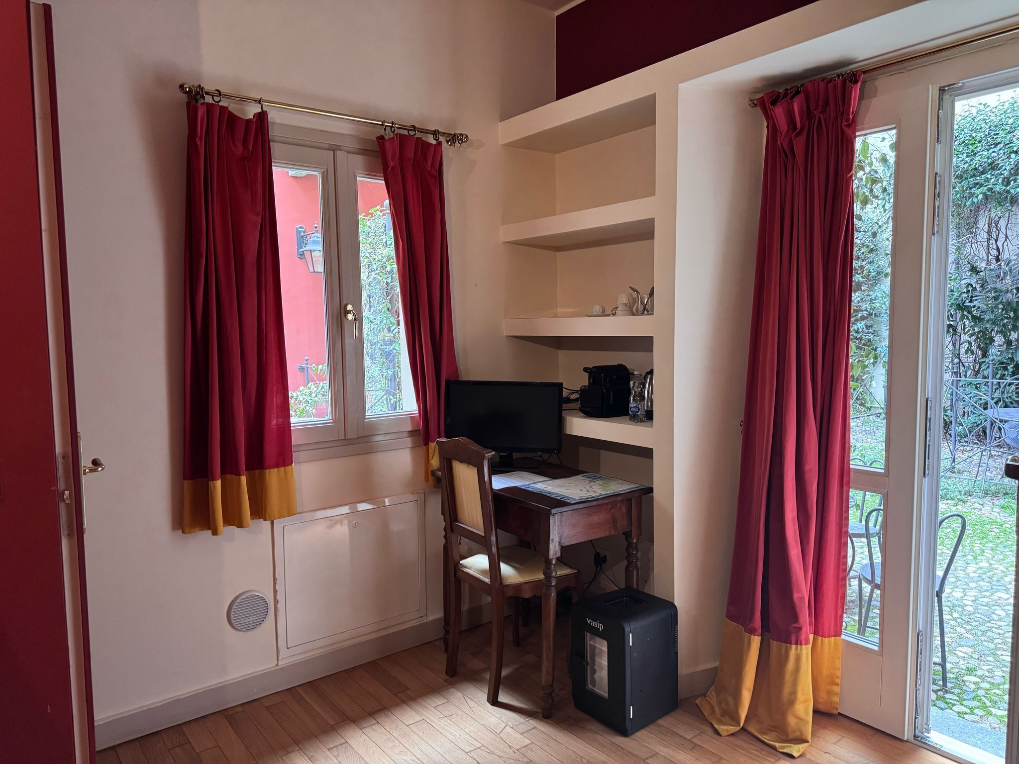 Une pièce comprenant un bureau, une chaise, un ordinateur et une valise.